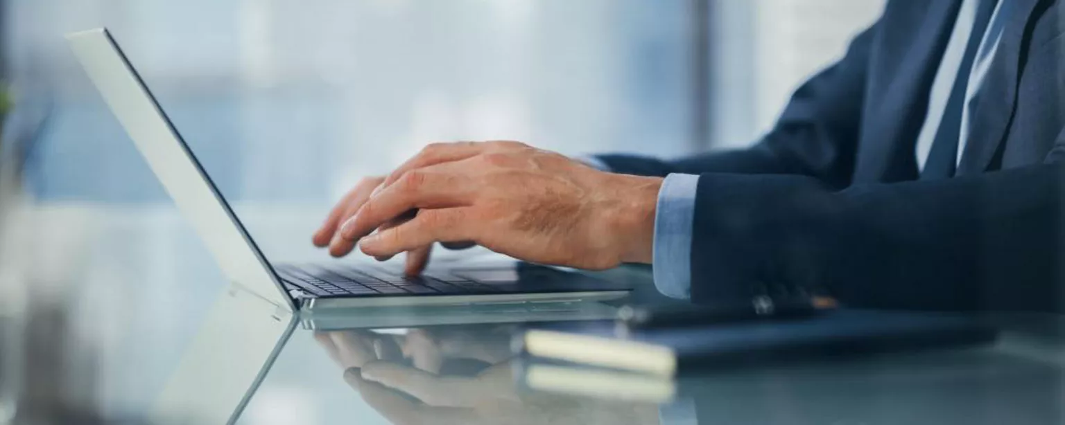 Man in suit at an office desk with laptop