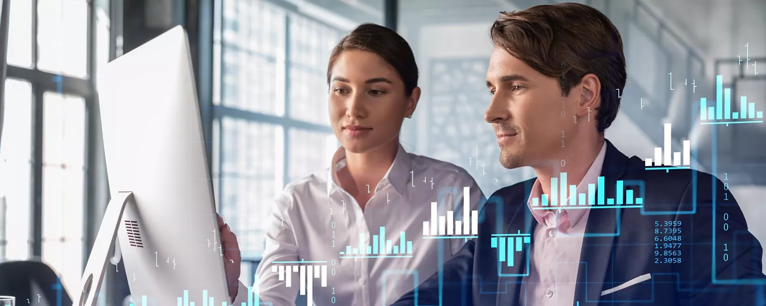 Male and female business professionals sit at a desk, looking at a computer monitor displaying holographic bar charts in front of them.