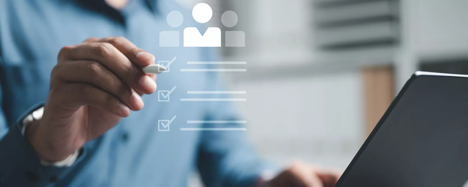 Hiring manager sits at a laptop evaluating candidate profiles using a digital checklist to find a candidate.