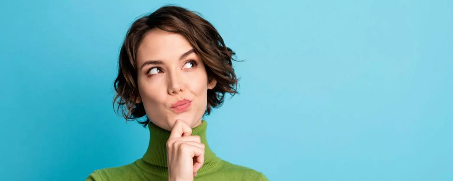 Young woman in a green turtleneck appears to contemplate the answer to a tough question.