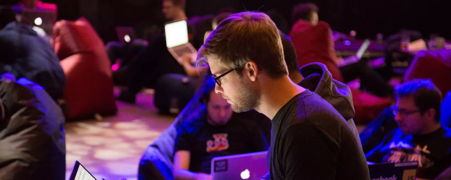 Ein Mann sitzt in einer Menschengruppe. Alle schauen in ihre Laptops. 