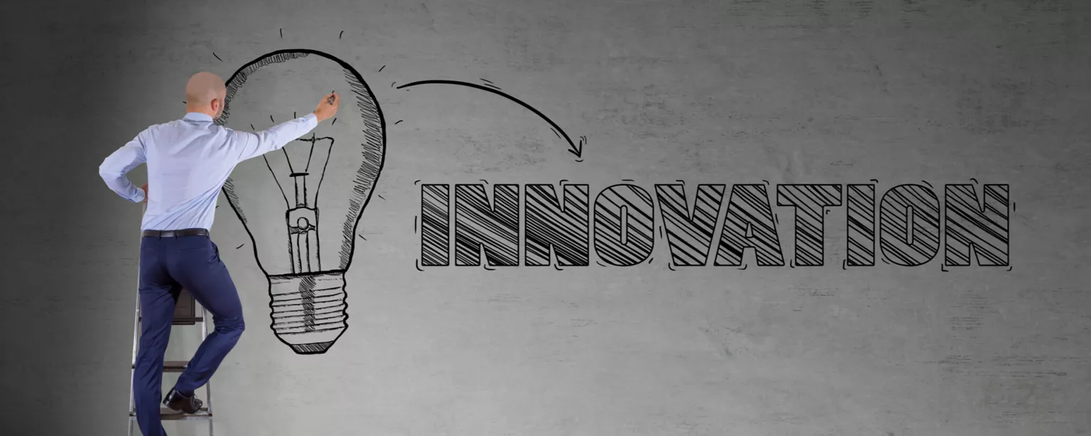 Man drawing lightbulb on wall and word innovation