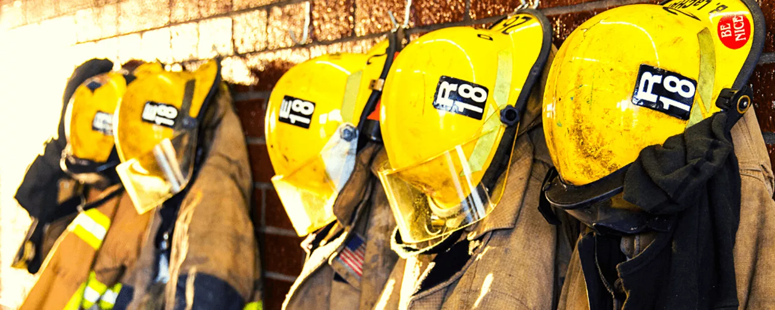 Mehrere Feuerwehr-Schutzanzüge sind in einer Reihe aufgehängt