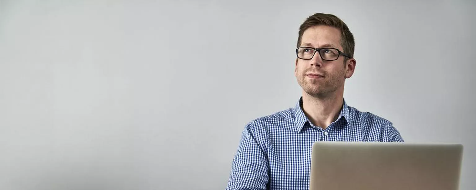 How to Succeed and Thrive as an Introvert at Work — man sitting at a desk and looking off to one side