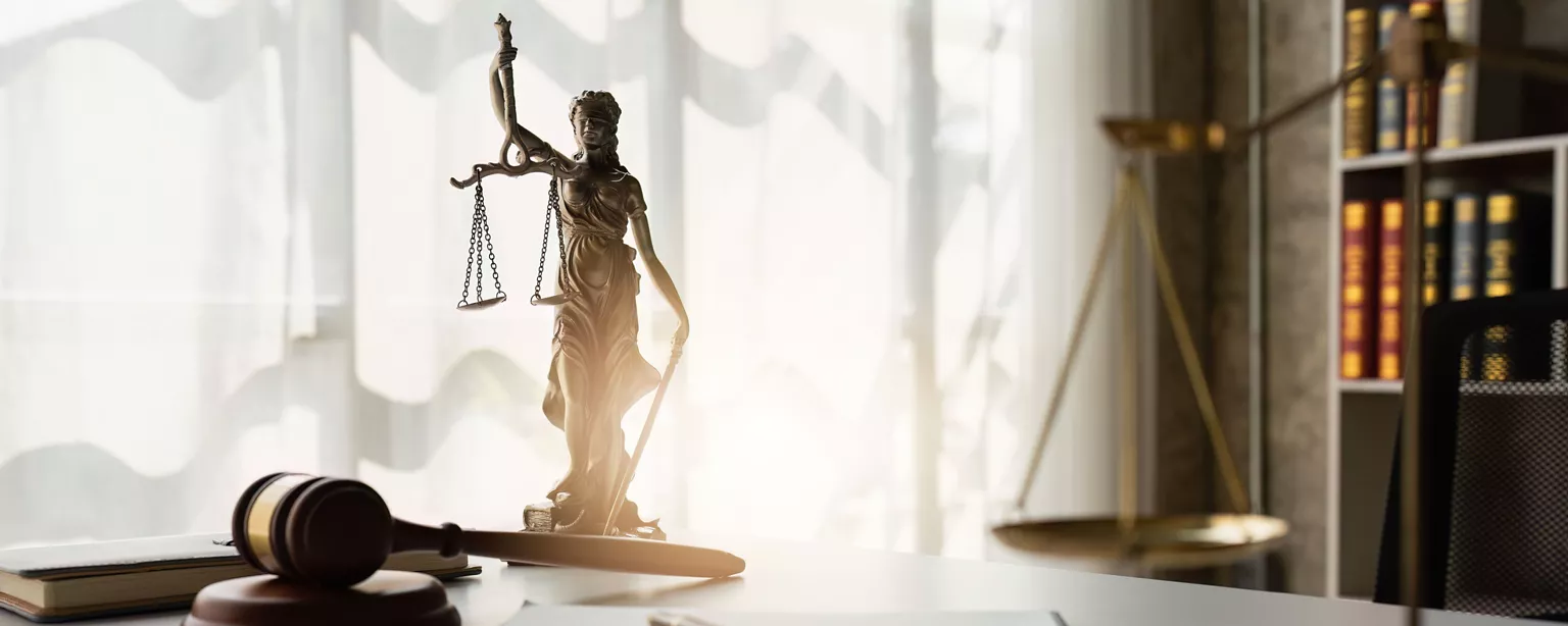 Lady justice statue sitting on a desk with a gavel.