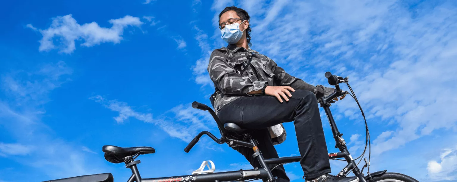 Person mit Mundschutz allein auf einem Tandem.