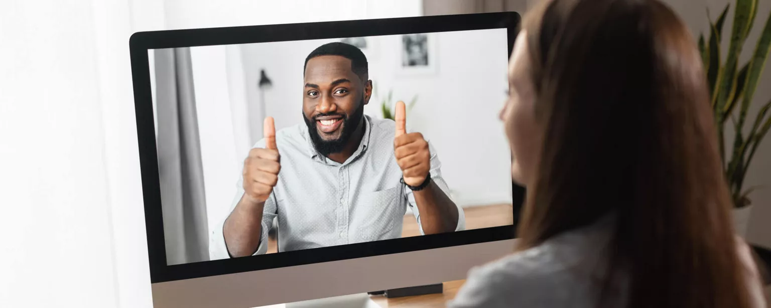 How to Create a Successful Leadership Development Program — woman looking at man on screen giving her thumbs up