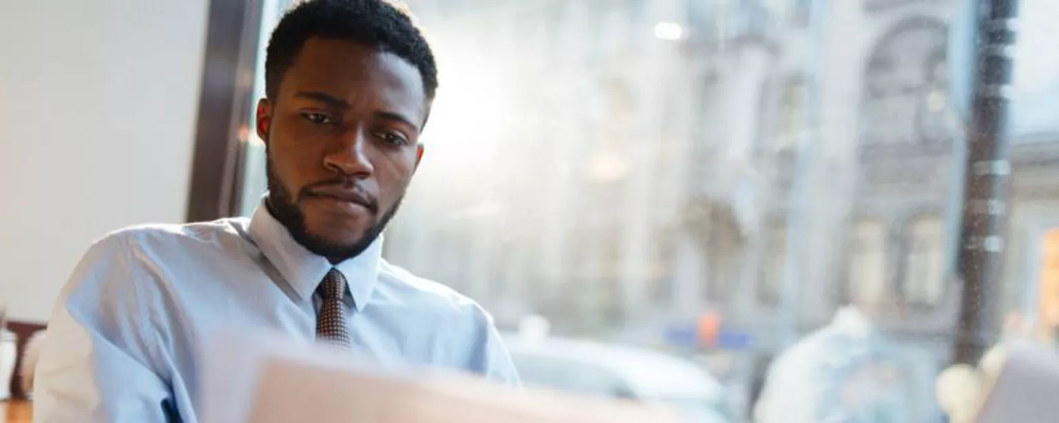 A hiring manager sitting at his desk and reviewing a resume.