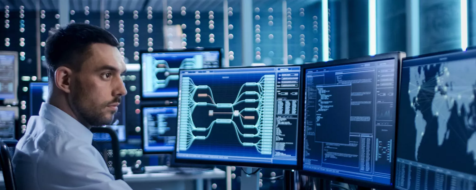 A cybersecurity professional looking at computer screens in a security operations center.