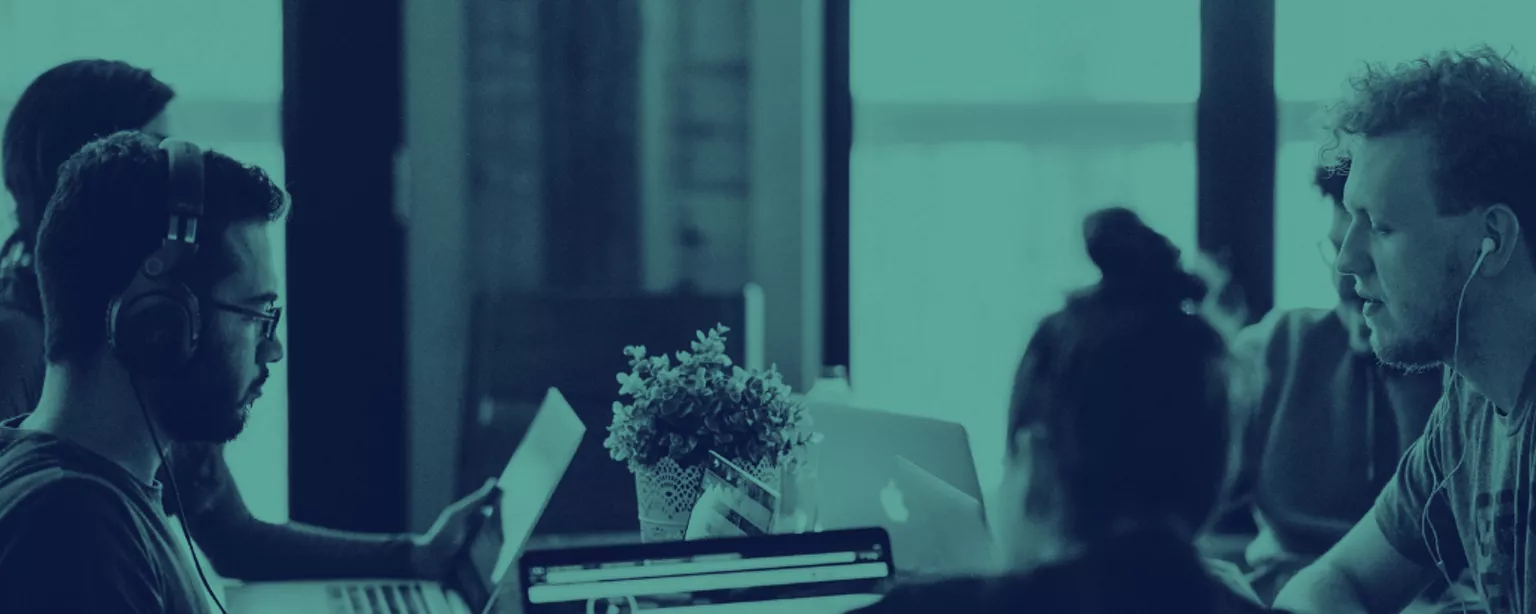 Two men and a woman sit with laptops in a collaborative working space