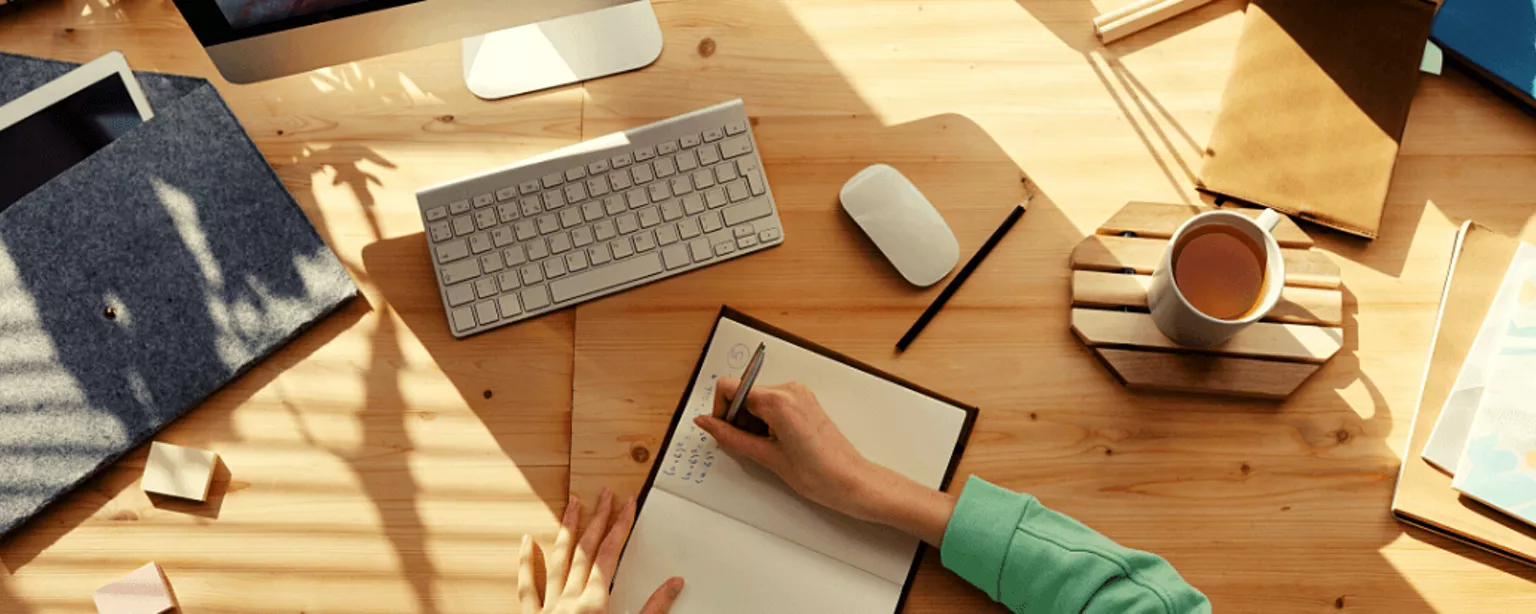 Eine Frau macht sich während eines Videocalls handschriftlich Notizen