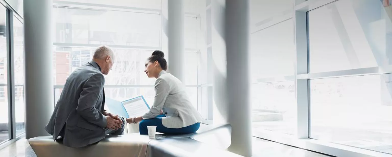 Two business people sitting on a bench having a meeting.