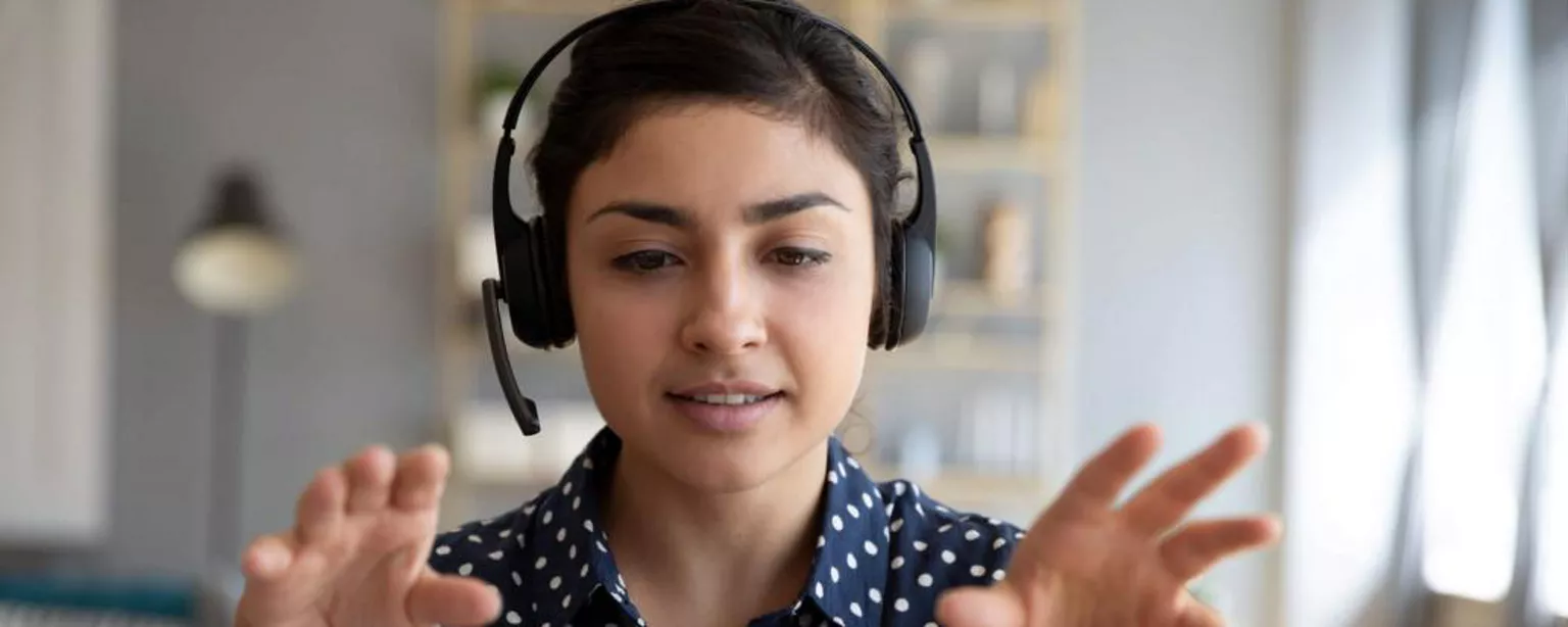 How to Make the Most of Online Events and Conferences — woman with headphones and expressive hands in front of laptop