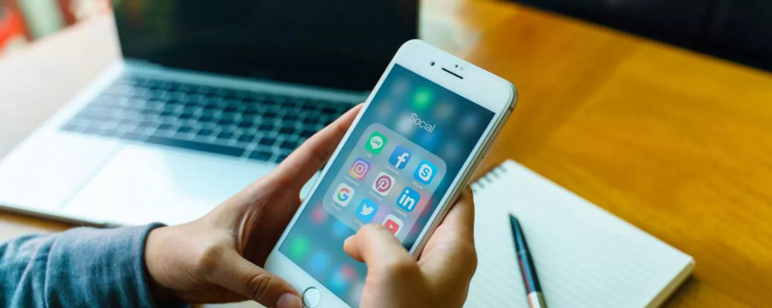 Have You Been Online Networking All Wrong? — hands holding iPhone with laptop, pencil and notebook in background