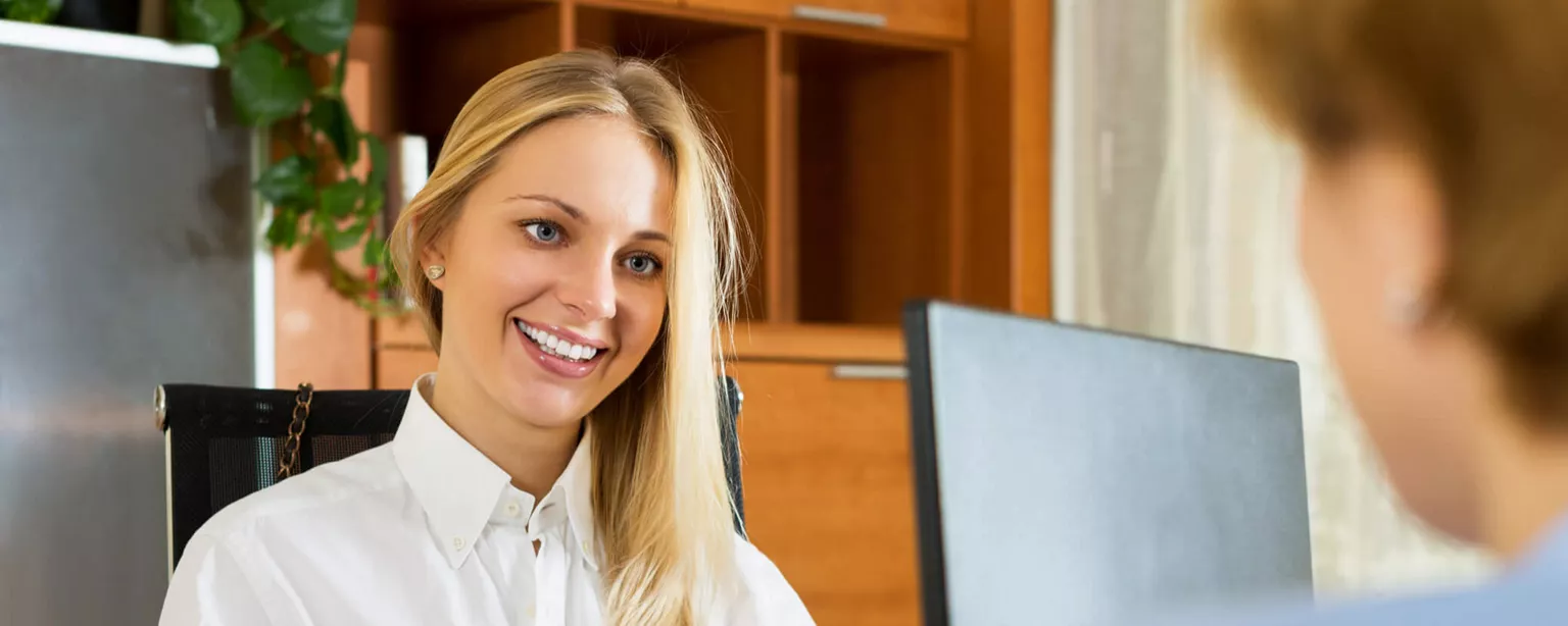 What Does a Payroll Clerk Do? Find Out If You Need One — woman smiling at another in office setting