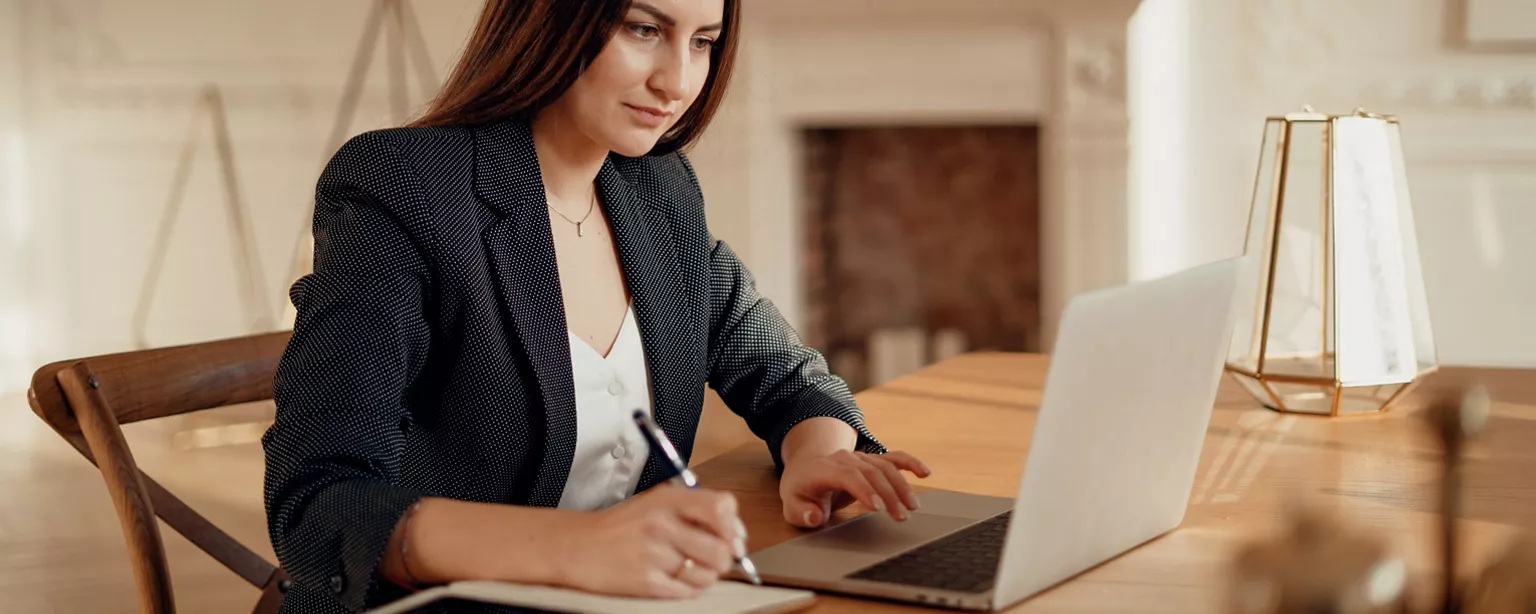 A woman works on a laptop at her desk