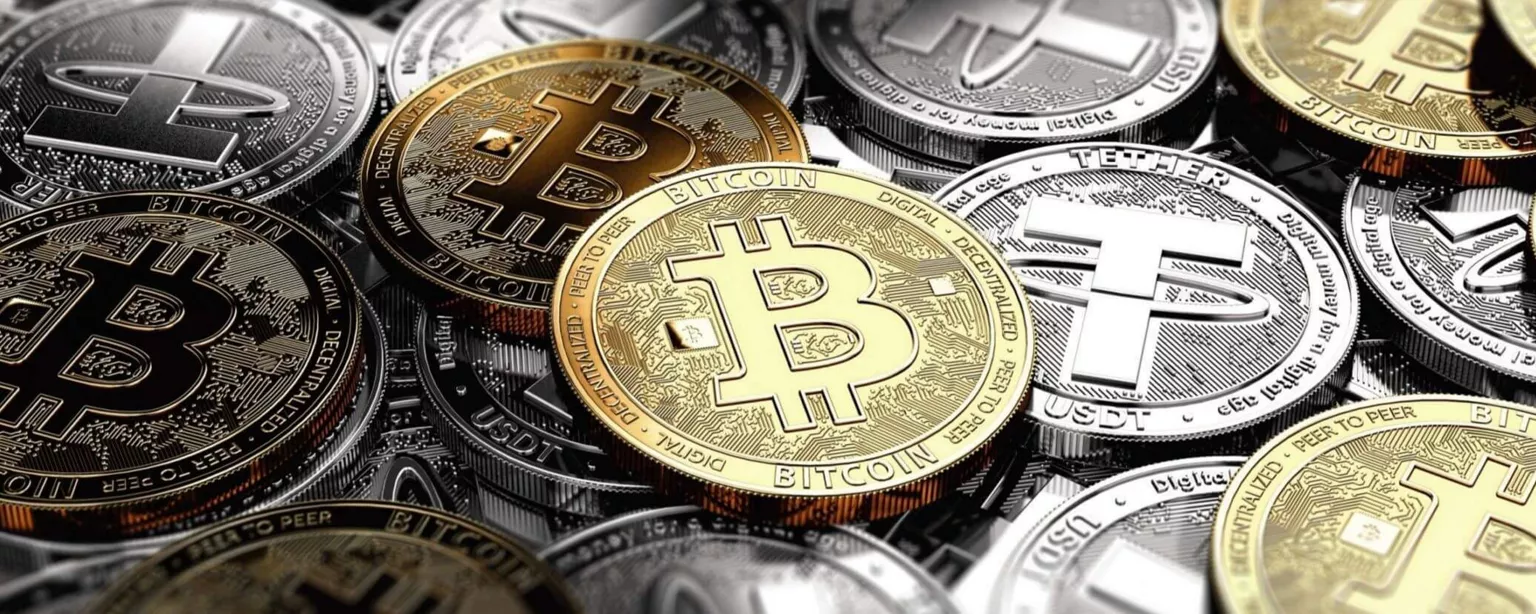 Cryptocurrency types shown as coins, including Bitcoin and Tether, in a pile.