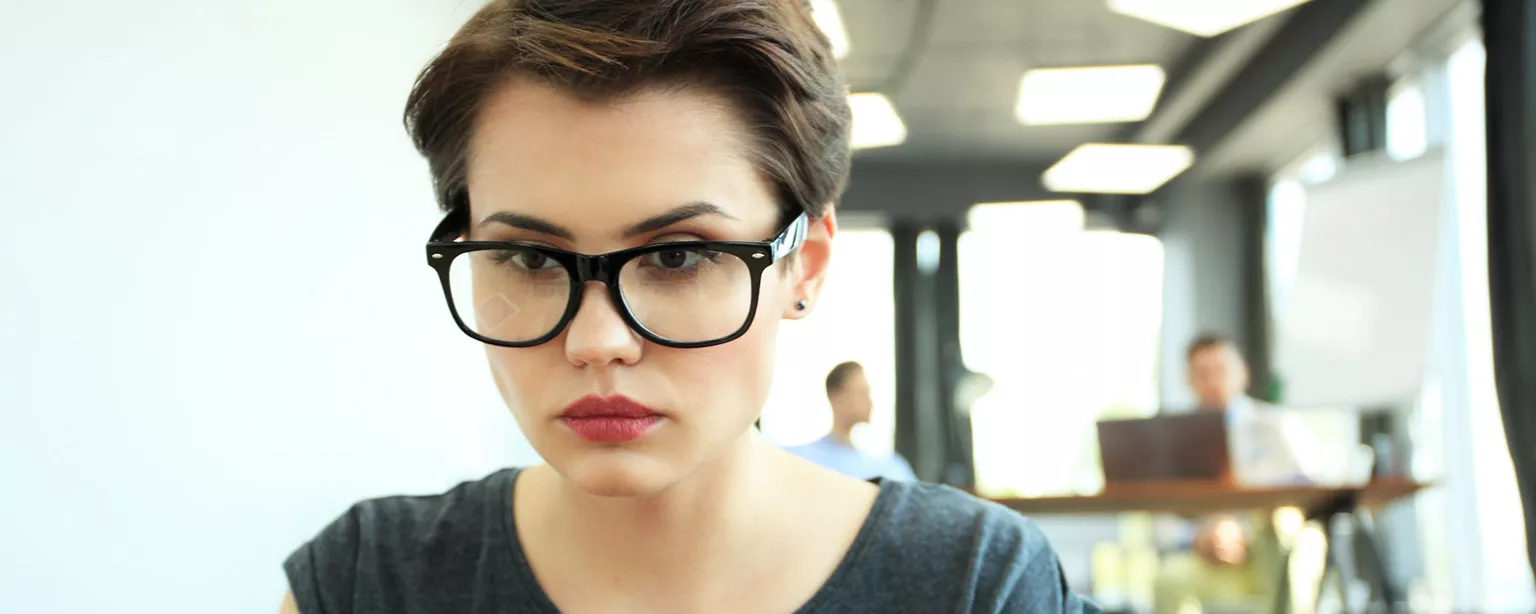 Young woman with glasses looking at a computer screen.