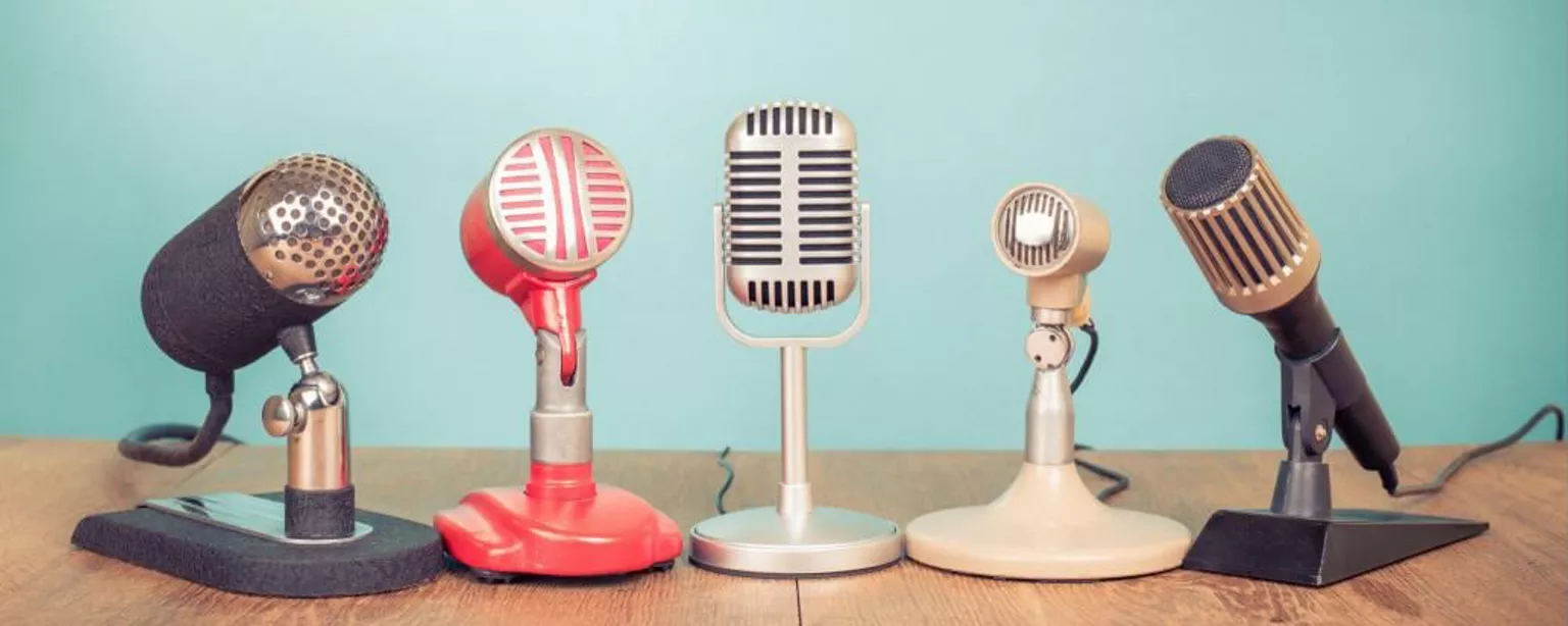 Five microphones lined up on a table. 