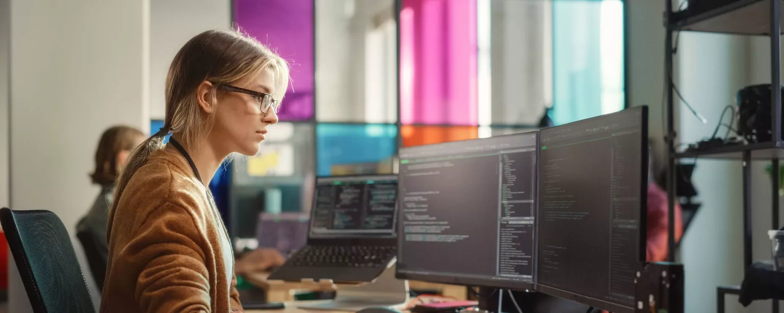 A web developer looks intensely at her computer screen while working on a project.