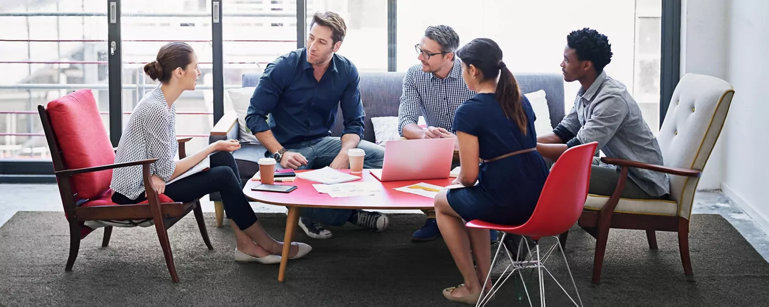 A project team that includes contract talent are sitting around a table in the office lounge discussing ideas.