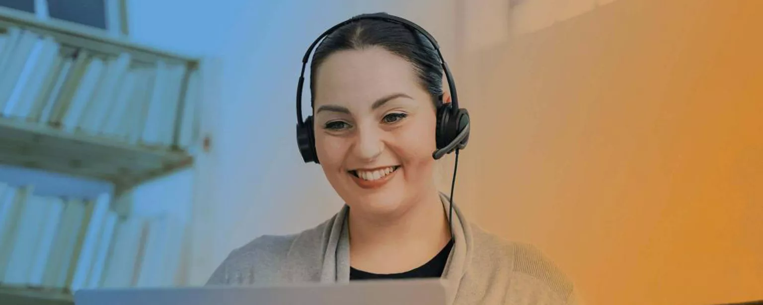 Remote worker wearing a headset and smiling at their screen.