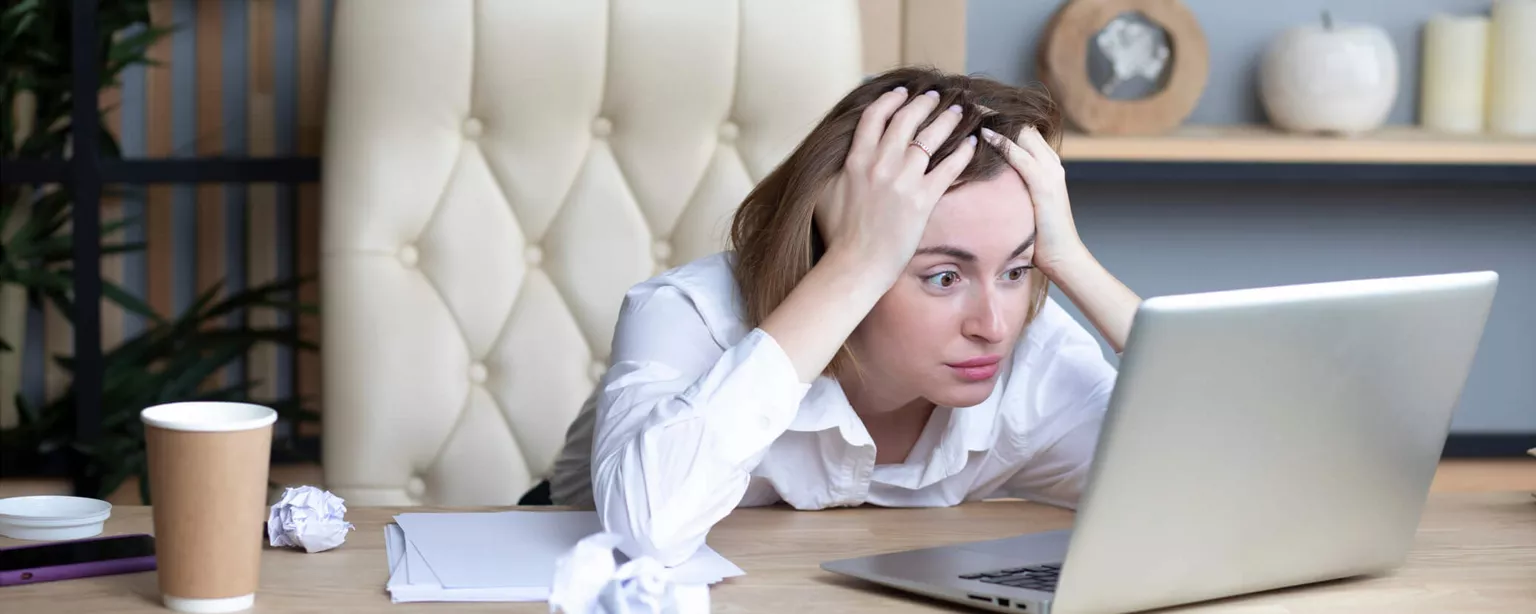 Resumania®: Does Your Resume Need Professional Help? — frustrated woman with crumpled paper and head in hands