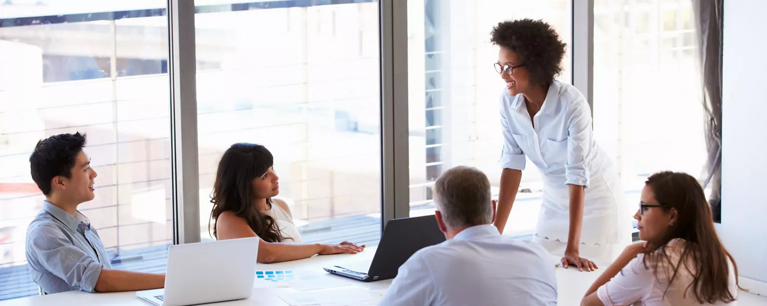 Woman standing and presenting to employees in a meeting.