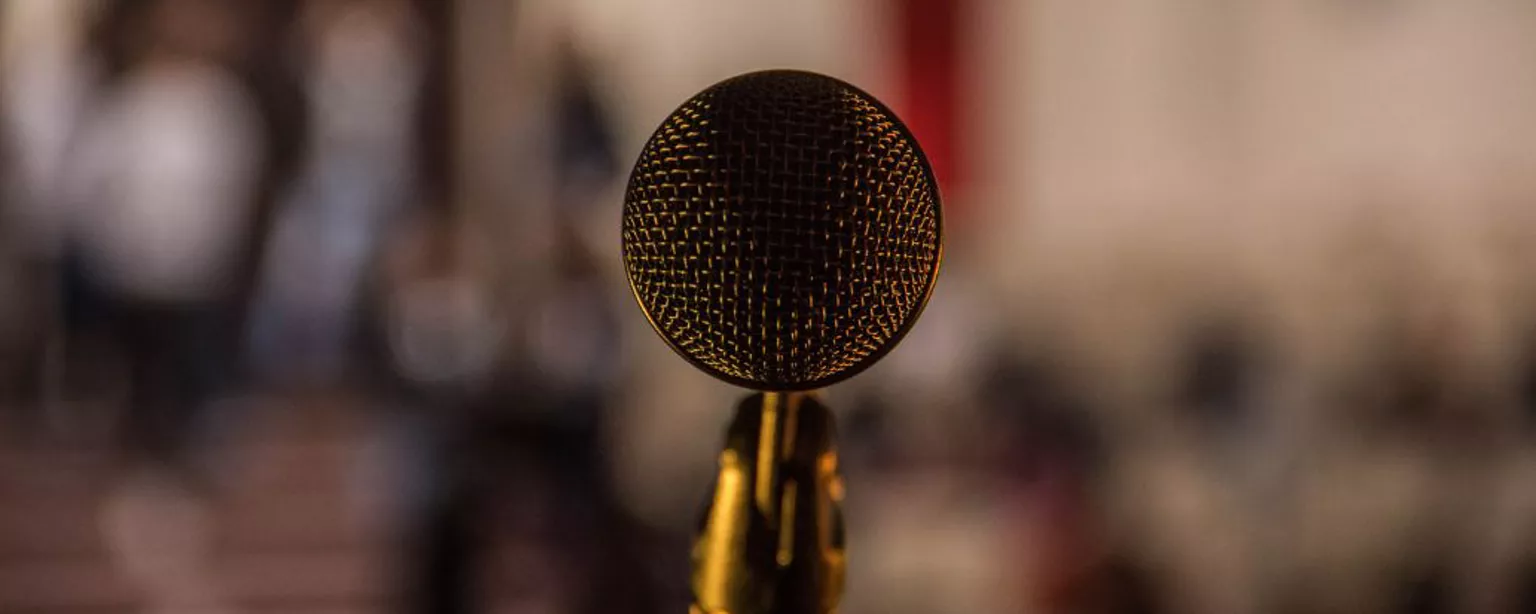 Ein goldenes Mikrofon steht auf einem Ständer vor unscharfem Hintergrund