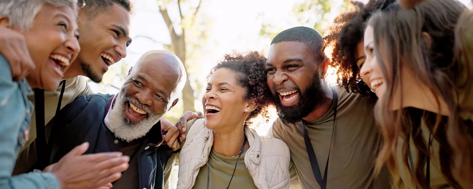 A group of non-profit employees standing close together outdoors, laughing and showing camaraderie during a service event.