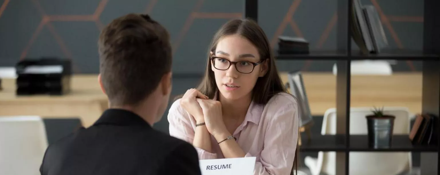 What Is a Staffing Agency? — Man holding resume talking to woman at office table