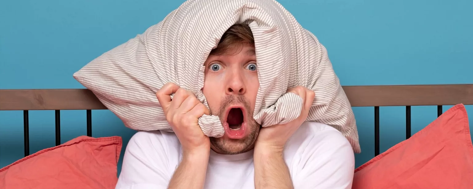 How to Beat the ‘Sunday Scaries’ and Calm Your Work Anxiety — man in bed with pillow over his head and his mouth wide open