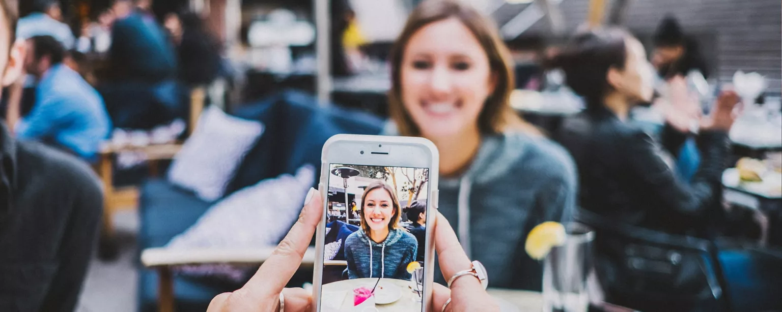 Junge Frau im Restaurant lässt ein Foto von sich für TikTok Bewerbung machen