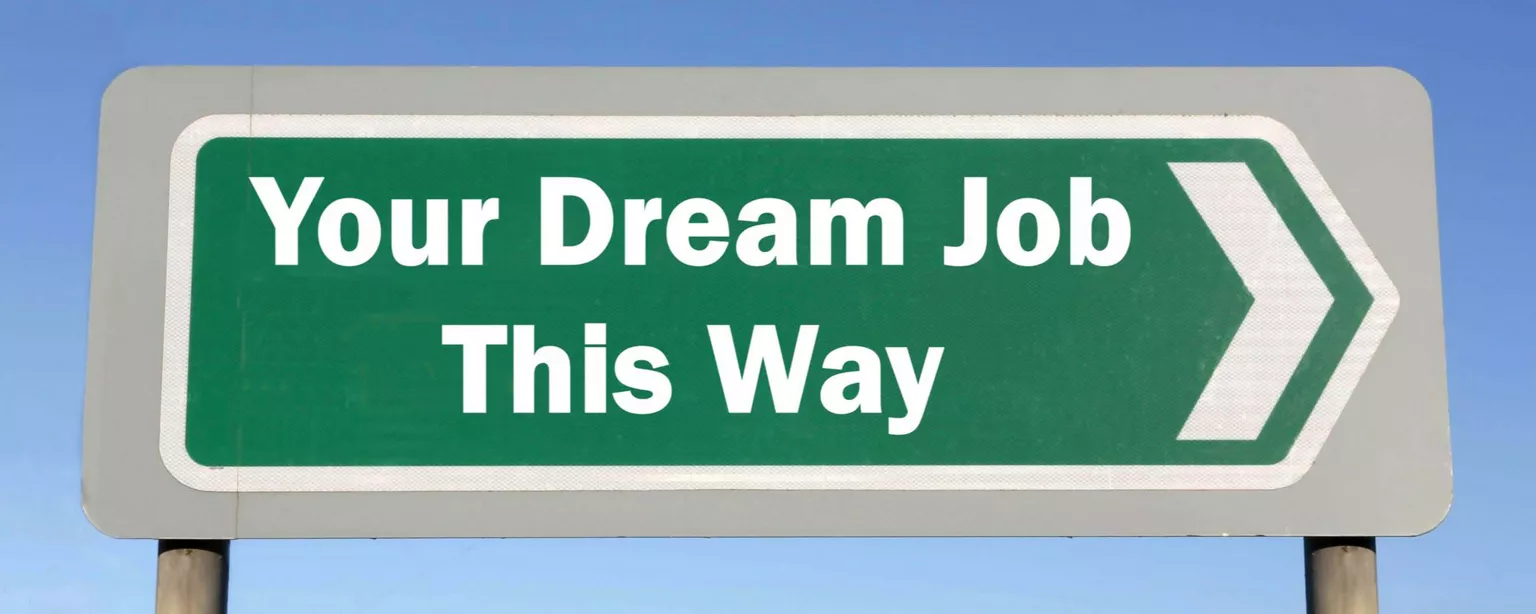 A green and white road sign shaped like an arrow that is point right and reads, "Your Dream Job This Way"