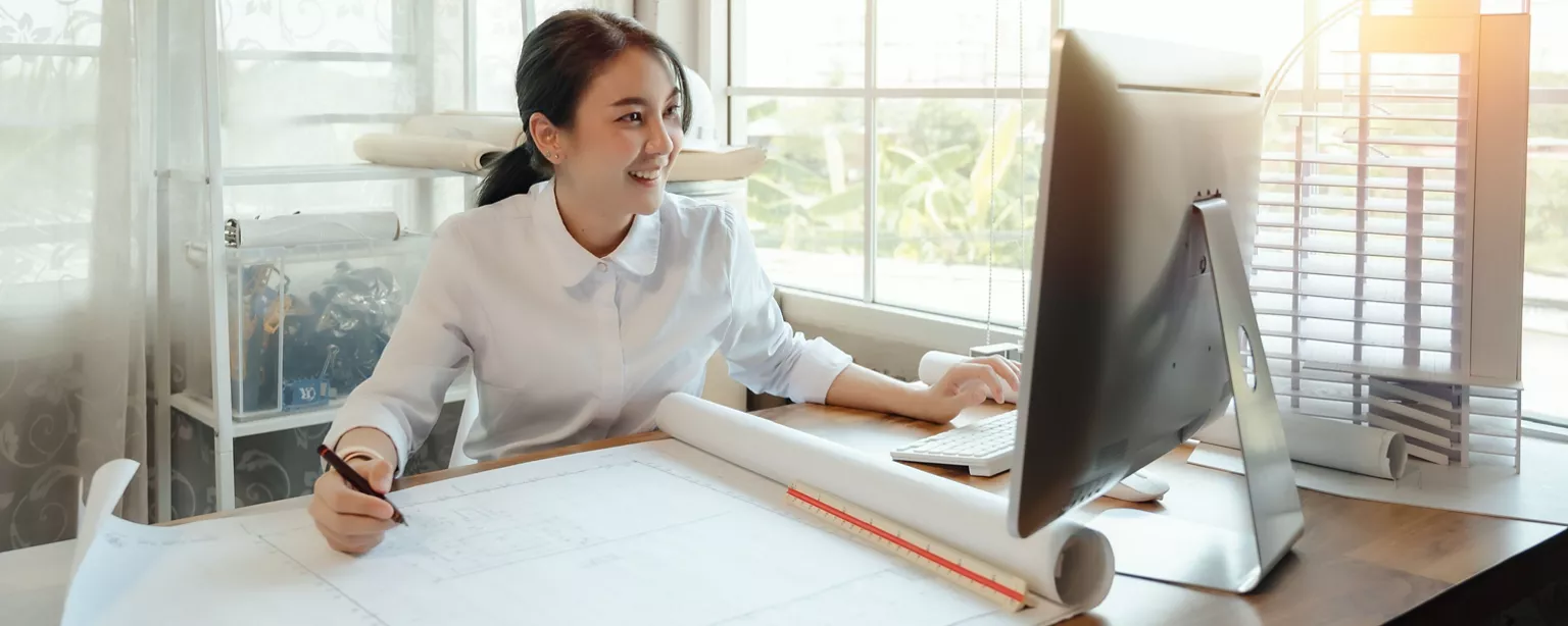 A female CFO in a white shirt sits at a desk in front of a montior.