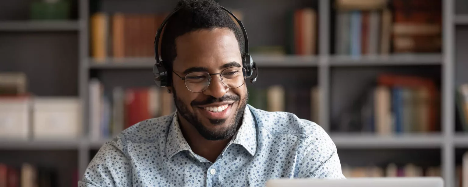 How to Upskill and Reskill Staff to Stay Competitive — man with headphones, pen and paper, laptop