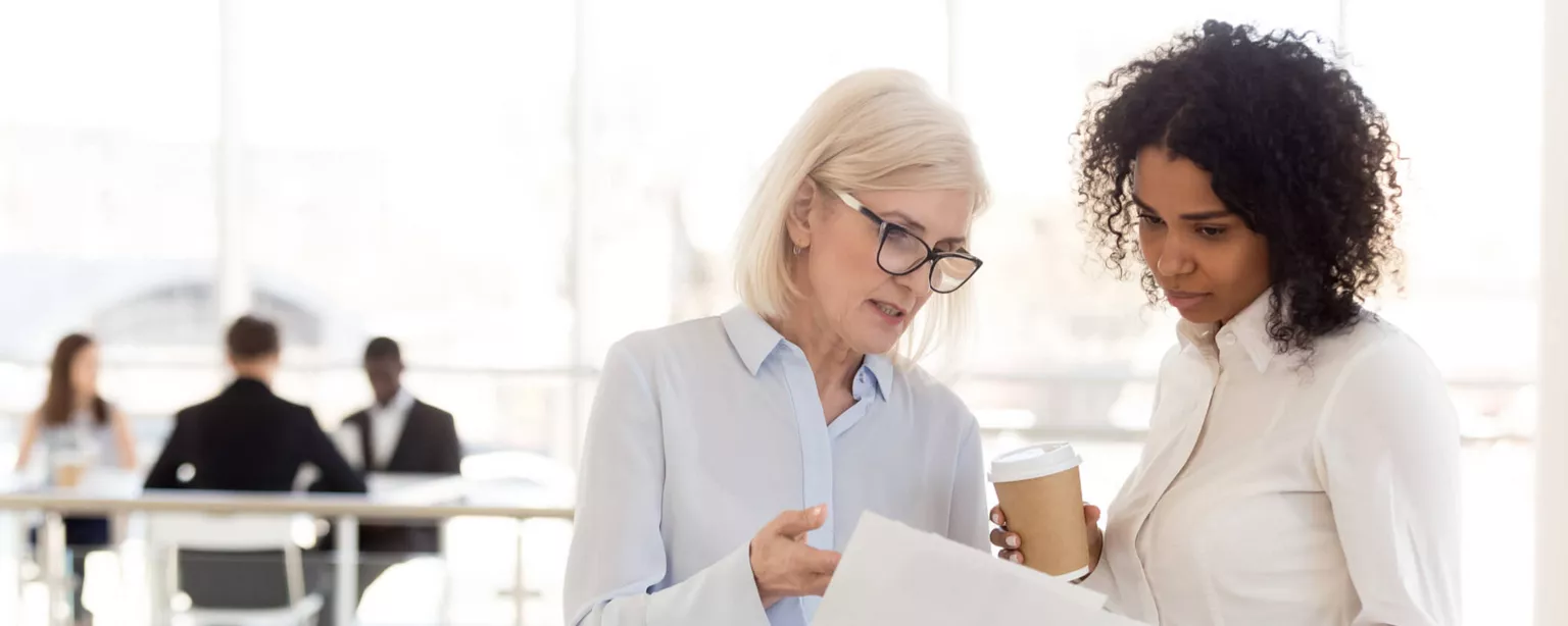 A female consultant showing a paper to a female client in an office setting.