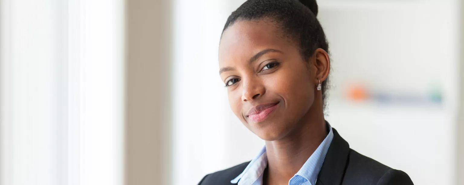 A professional woman smiles with confidence in an office setting.