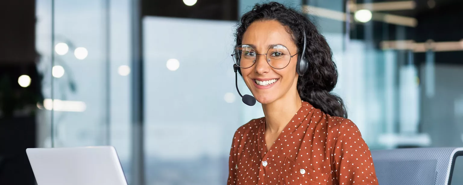 How to Become a Medical Credentialing Specialist — Woman with a headset sitting at a desk with a computer