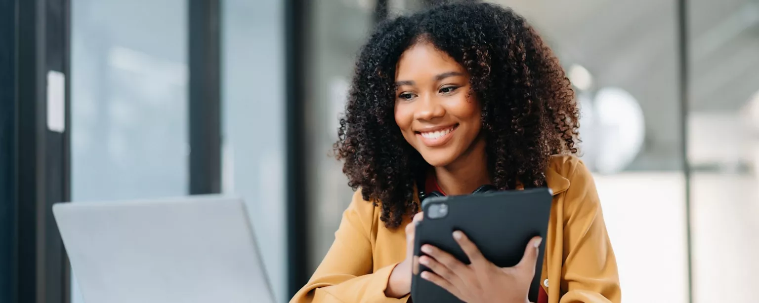 A woman smiles as she sits at her desk and studies for an accounting certification exam.