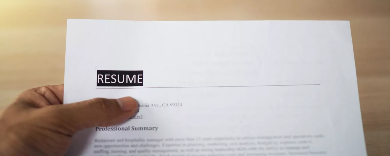 What Your Accounting Resume Should Look Like This Year — hand holding sheet with word RESUME