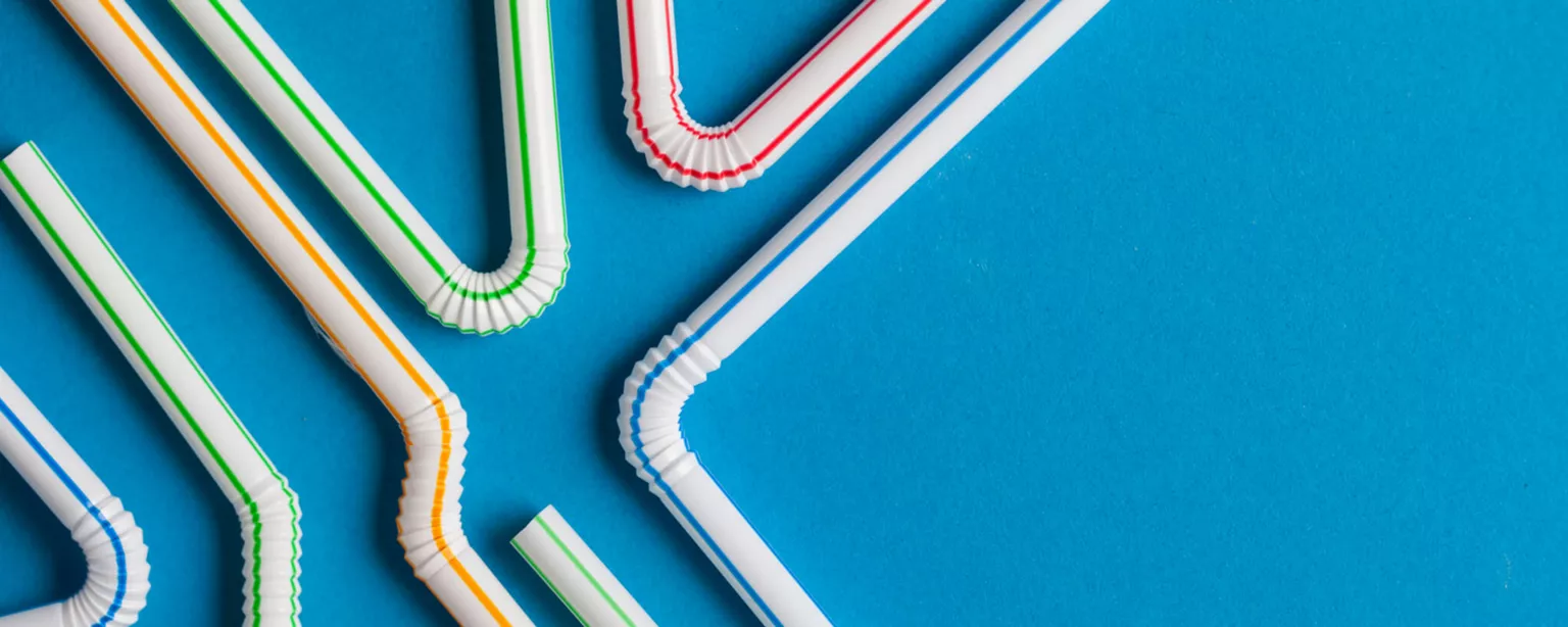 Several plastic straws with bendable necks and different colored stripes are displayed in a variety of positions against a blue background.