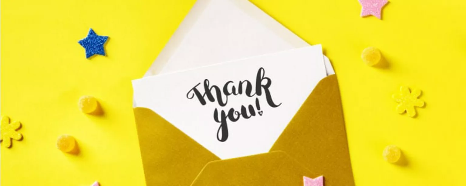 A thank-you note is seen partially enclosed in a brown envelope against a yellow background.