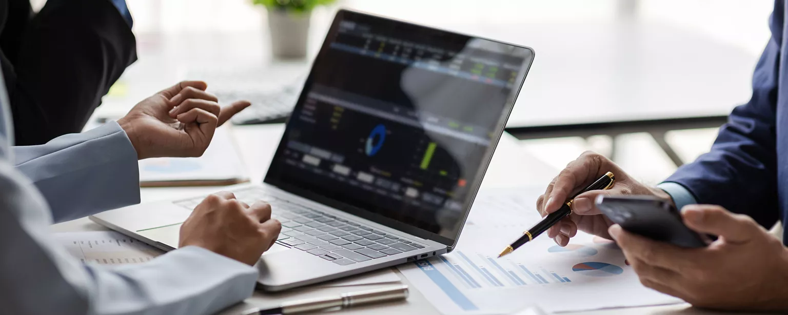 A finance team at a small business reviews AI-driven data analysis results on a laptop screen.