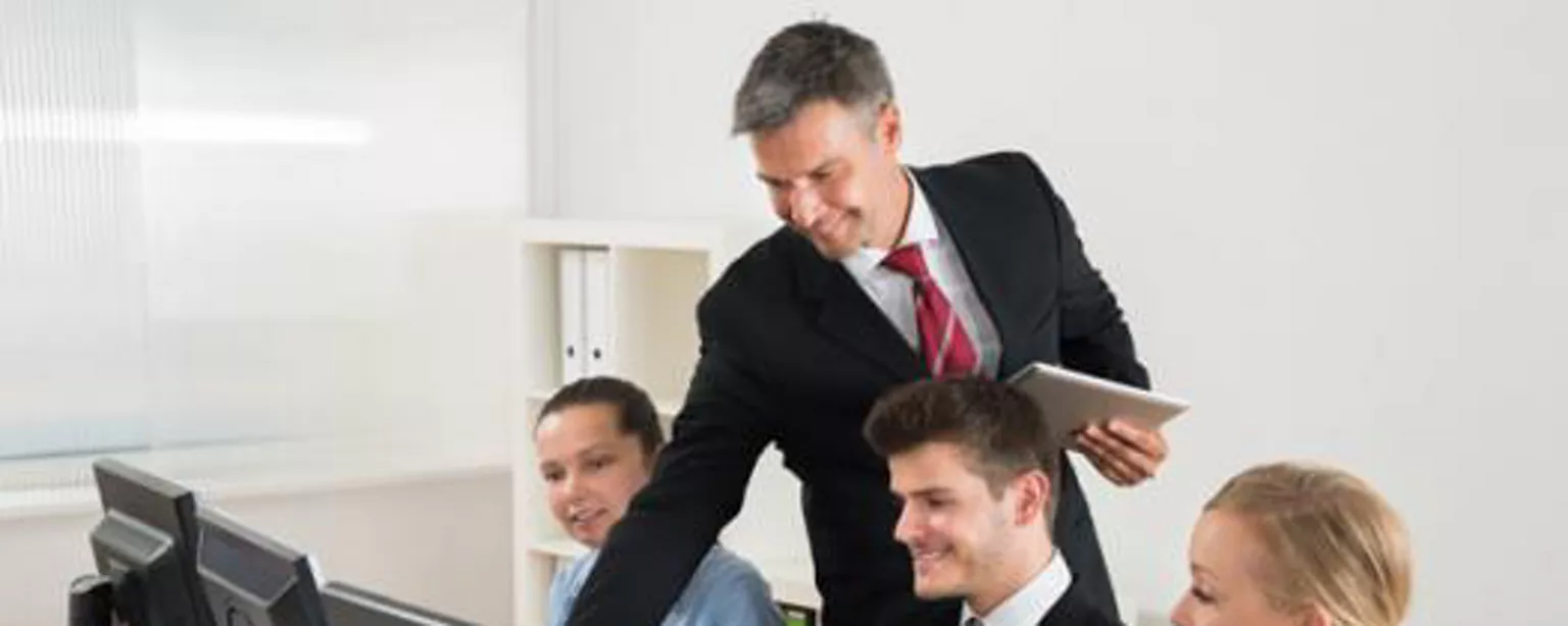 3 professionals at computers receiving direction from boss