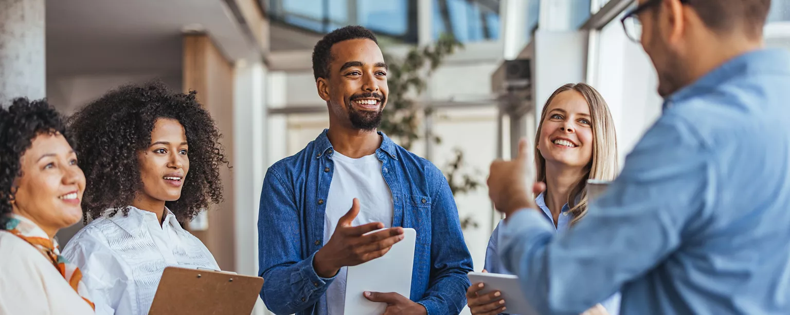 A diverse group of professionals smiling and talking together in an office.