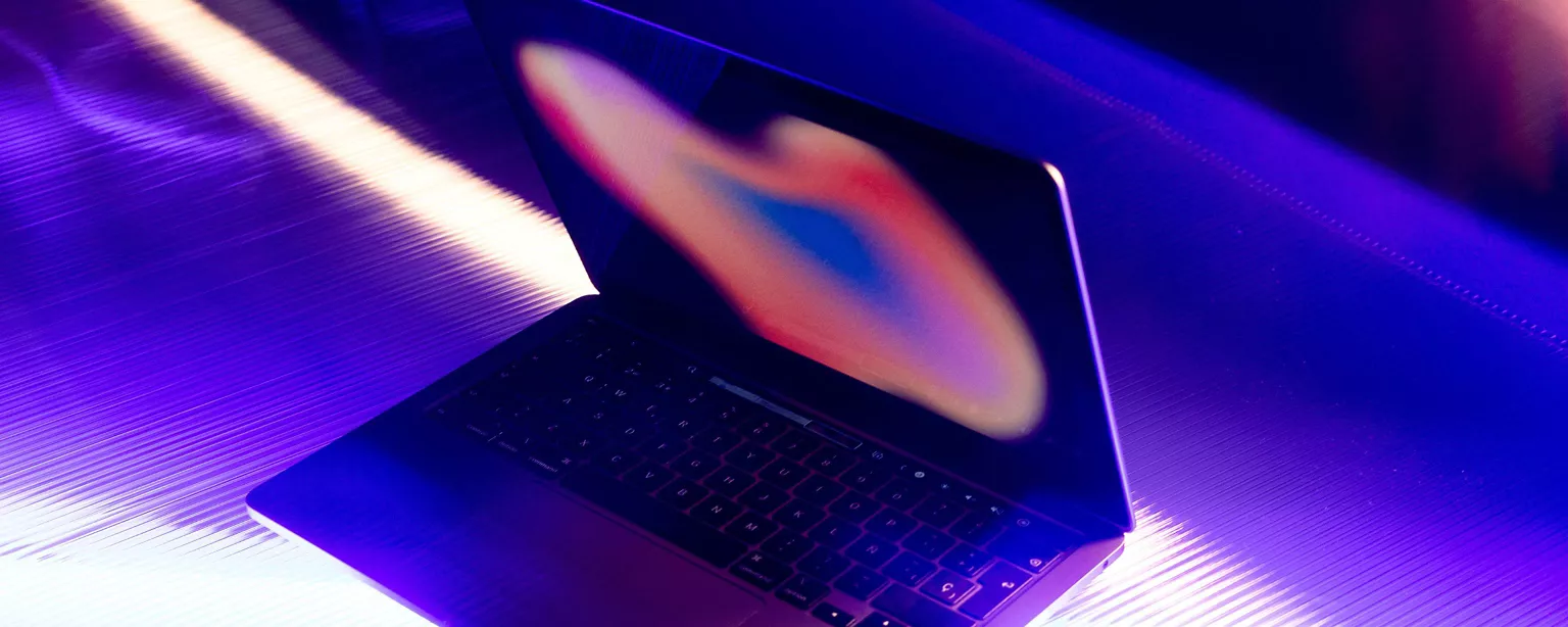 A sleek laptop with a vibrant, abstract display screen emits a purple glow.