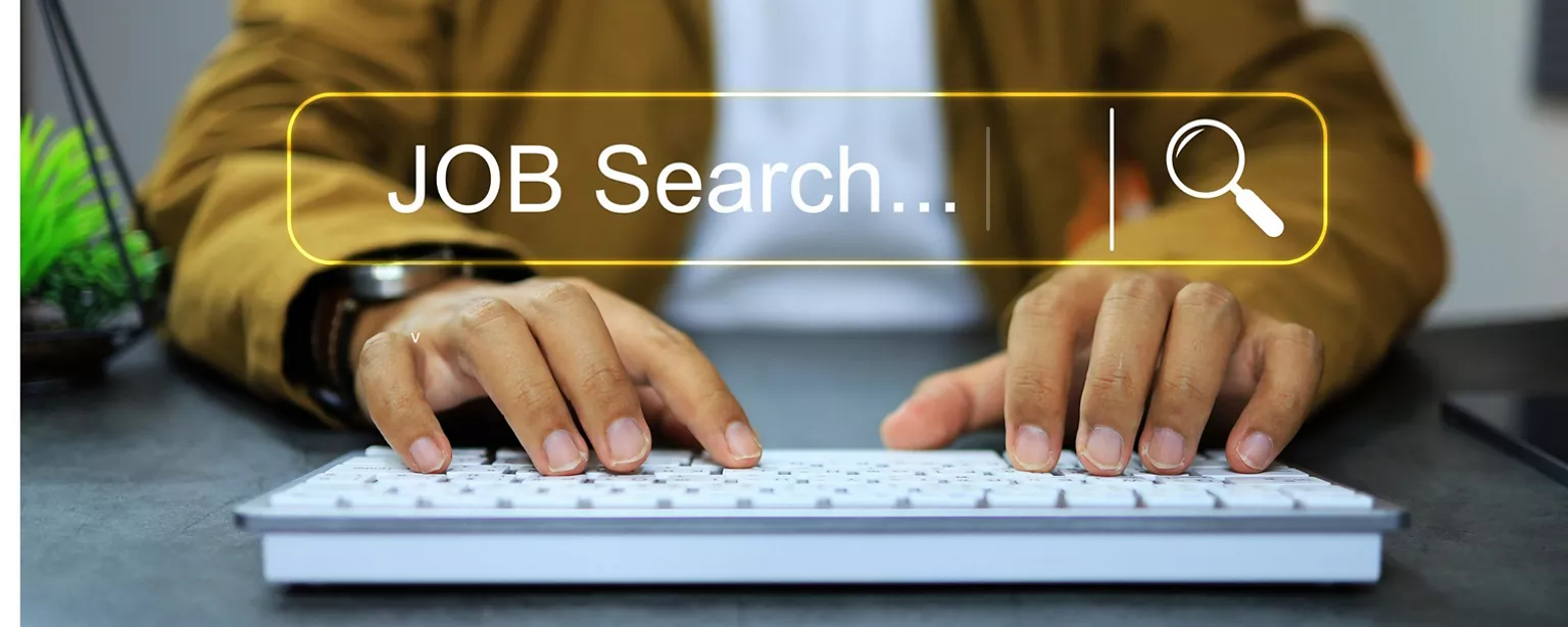 Mann sitzt vor dem Laptop und gibt Jobsuche ein.