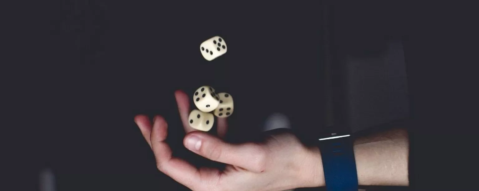 Hand mit Uhr am Handgelenk wirft vier Würfel in die Höhe