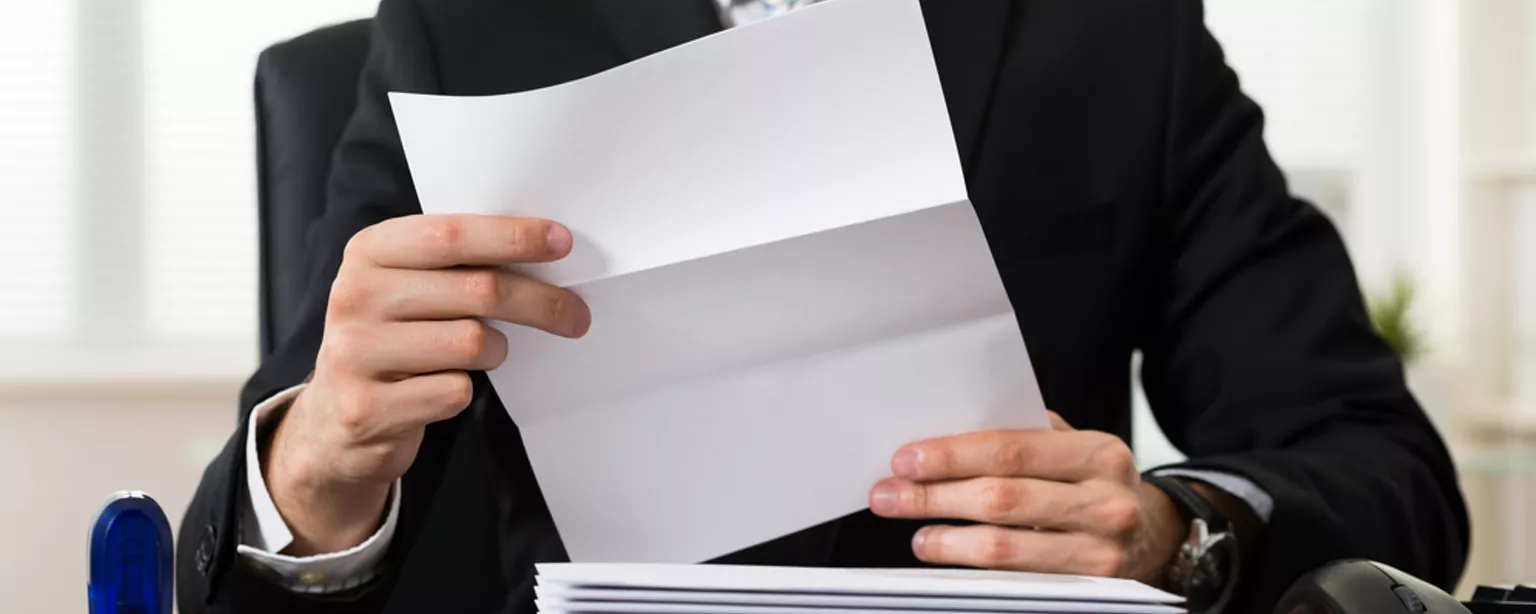 A businessperson at a desk reviews a cover letter.